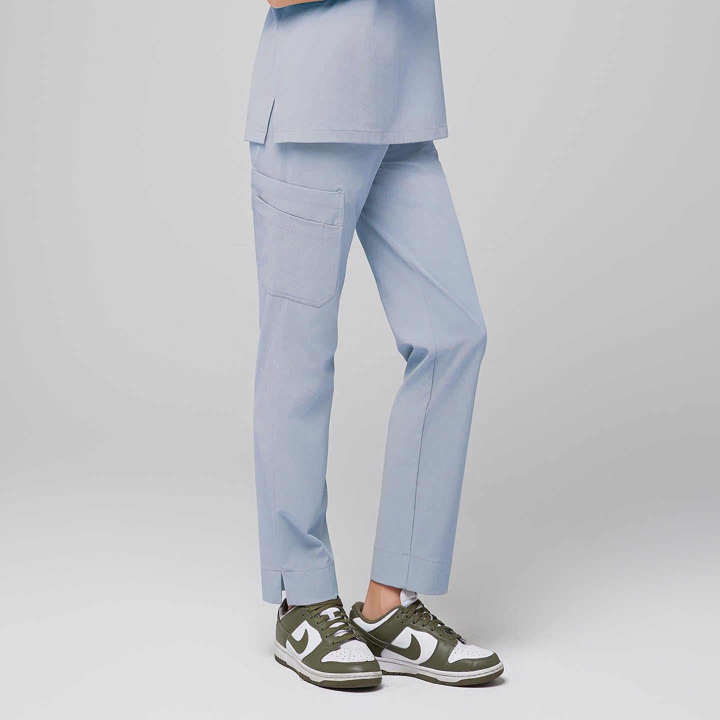 Side view of cool gray scrub pants with side pocket and split hem, paired with green and white sneakers,Cool Gray