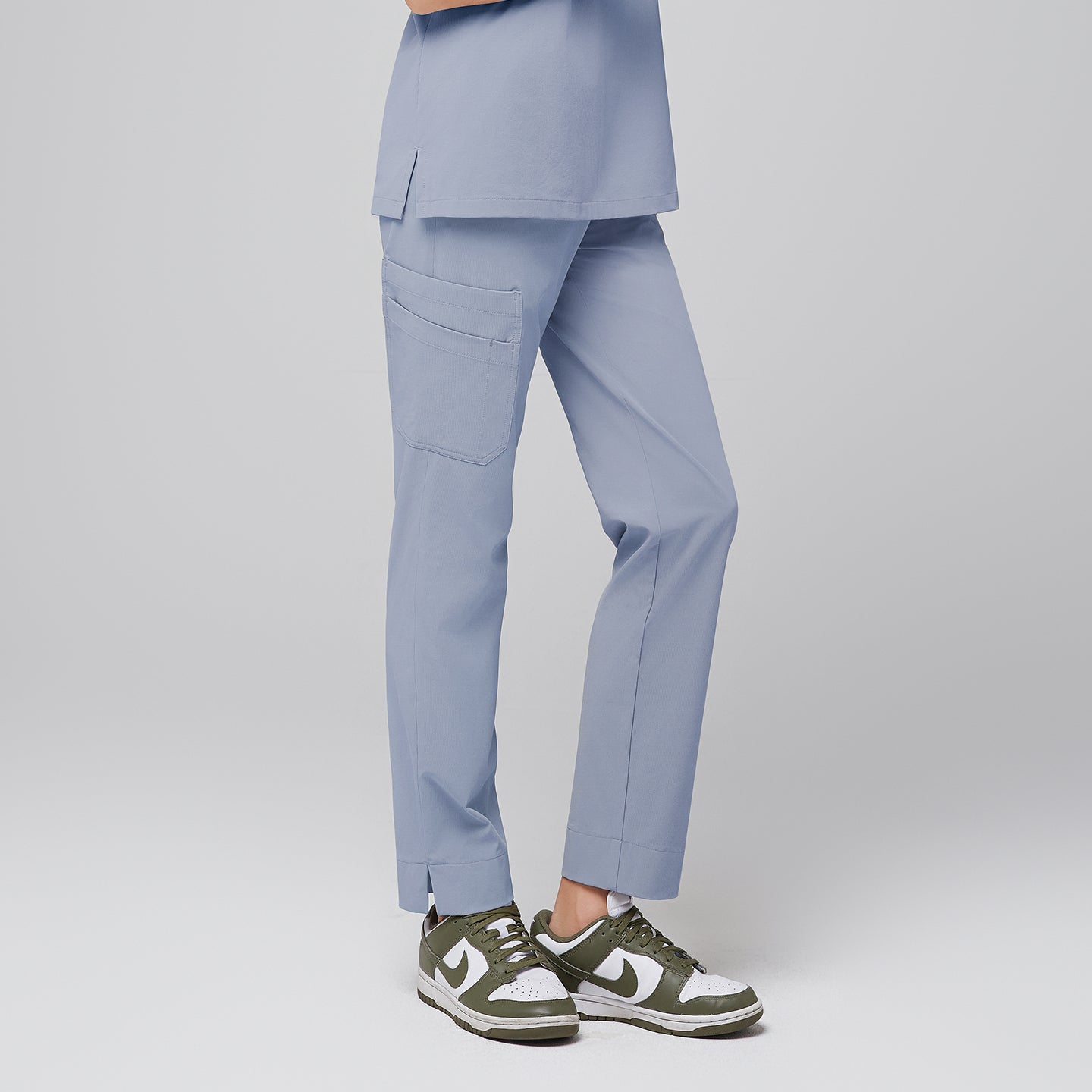 Side view of cool gray scrub pants with side pocket and split hem, paired with green and white sneakers,Cool Gray