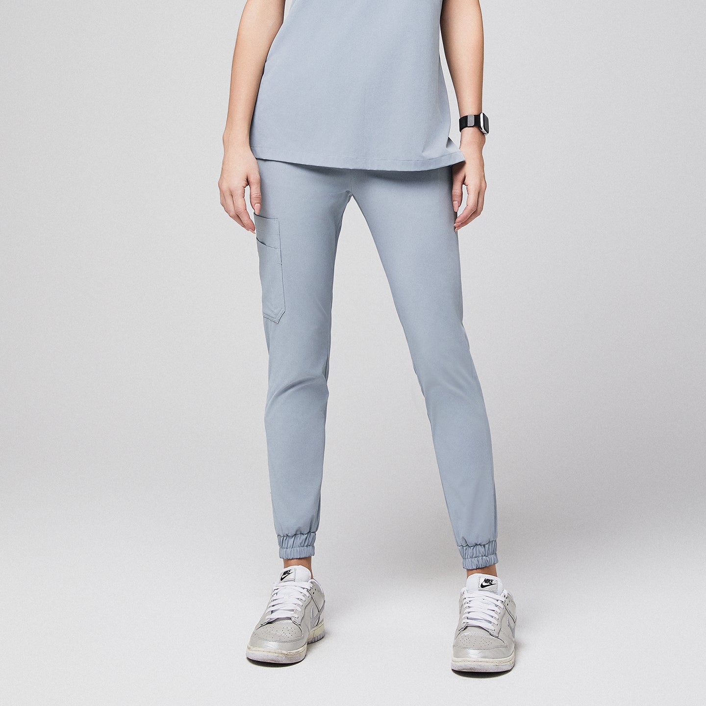 Medical professional wearing jogger-style scrub pants with side pocket and sneakers,Cool Gray