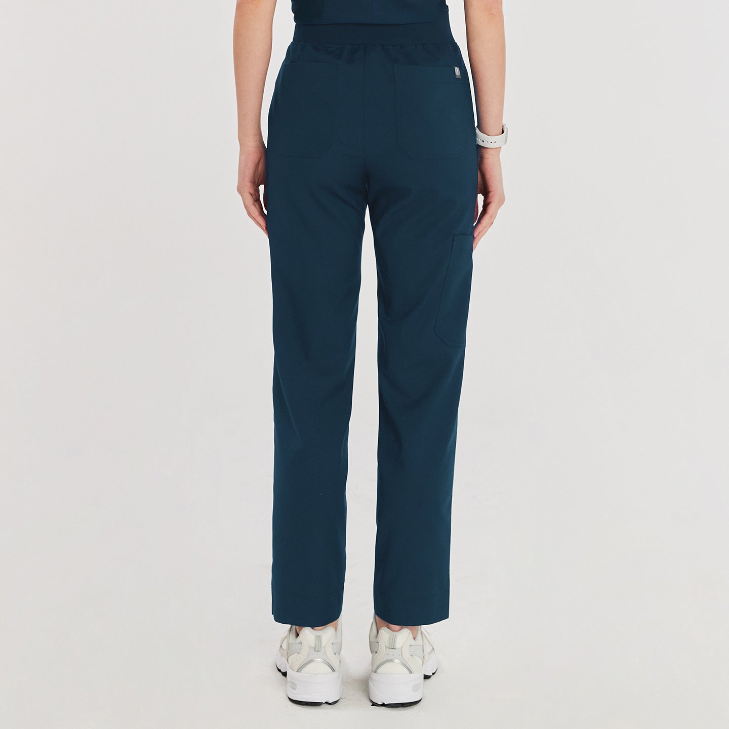 Woman wearing dark blue zipper slit scrub pants, shown from the back. The pants feature back pockets and a comfortable elastic waistband,Dark Blue