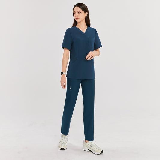Woman wearing dark blue zipper slit scrub pants paired with a matching V-neck short sleeve top, showing the full front view,Dark Blue
