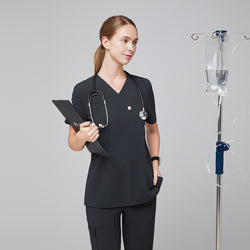 Image of Female healthcare professional wearing a dark gray V-neck scrub top and pants, holding a clipboard with an IV stand in the background,Deep Gray