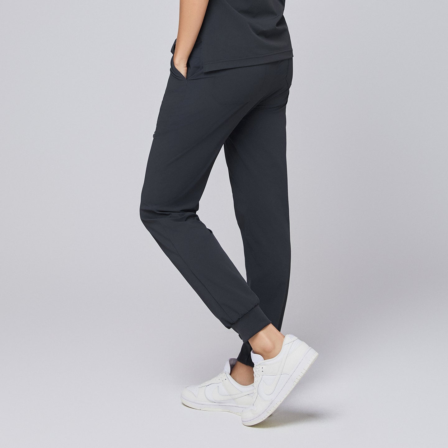 ack view of deep gray jogger scrub pants with elastic cuffs and back pockets, paired with white sneakers,Deep Gray