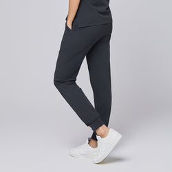 Image of ack view of deep gray jogger scrub pants with elastic cuffs and back pockets, paired with white sneakers,Deep Gray