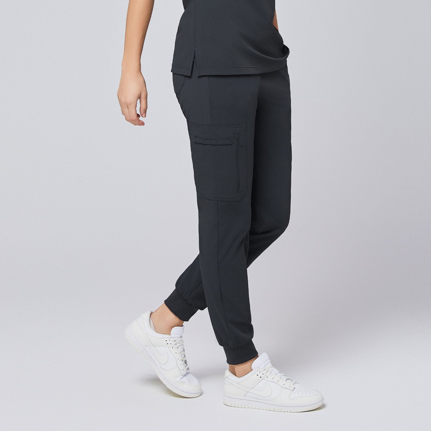 Side view of deep gray jogger scrub pants with zipper pocket and elastic cuffs, styled with white sneakers,Deep Gray