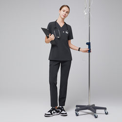 Image of Healthcare professional wearing a scrub set with a V-neck top and zipper pocket pants, holding a clipboard and stethoscope, standing next to an IV pole,Deep Gray