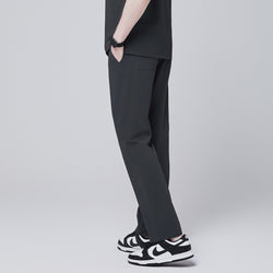 Image of Rear side view of deep gray straight scrub pants with back pocket details, paired with black and white sneakers, modeled against a neutral gray background,Deep Gray