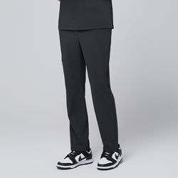 Image of Side view of deep gray straight scrub pants showcasing a minimalist zipper pocket design, styled with black and white sneakers, modeled against a neutral gray backdrop,Deep Gray