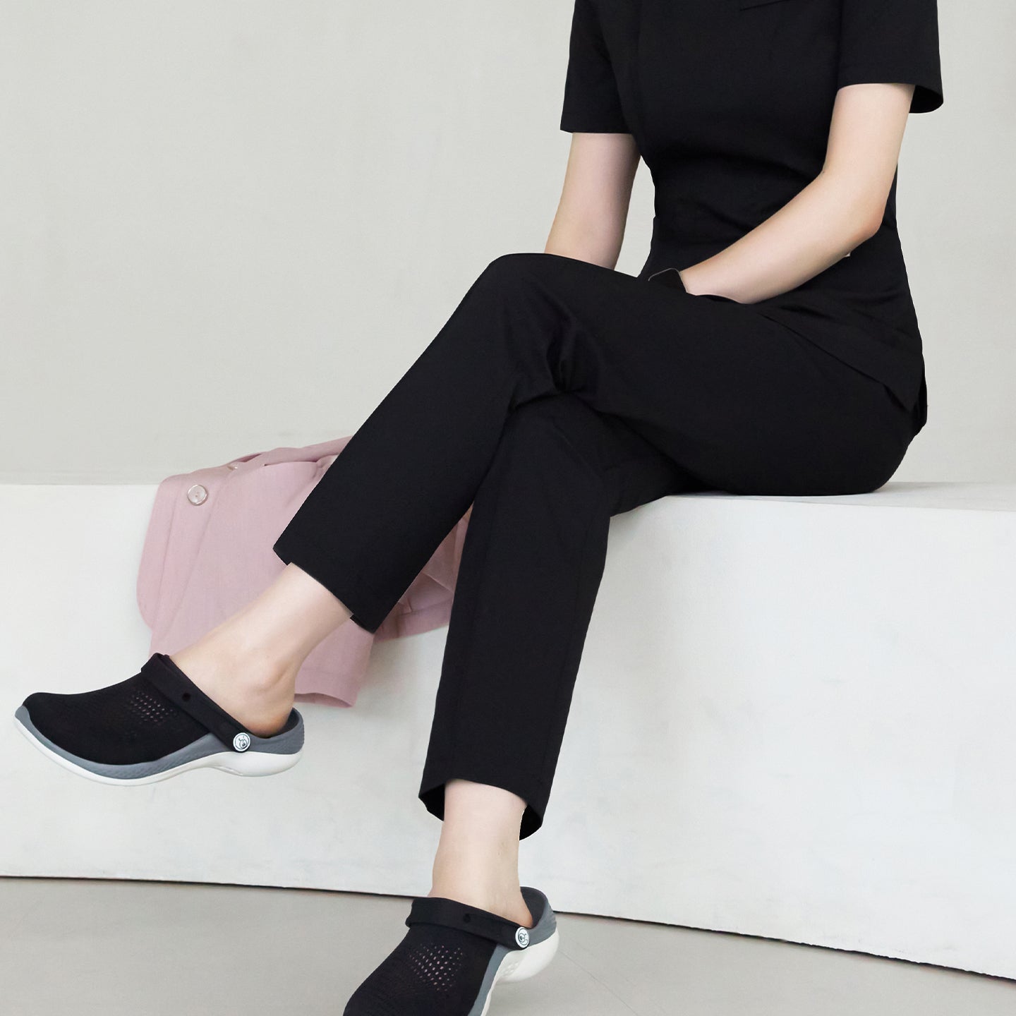 A woman sitting, wearing Eco Black Line Banding Scrub Pants with matching top, showing a relaxed pose and the full length of the pants,Eco Black