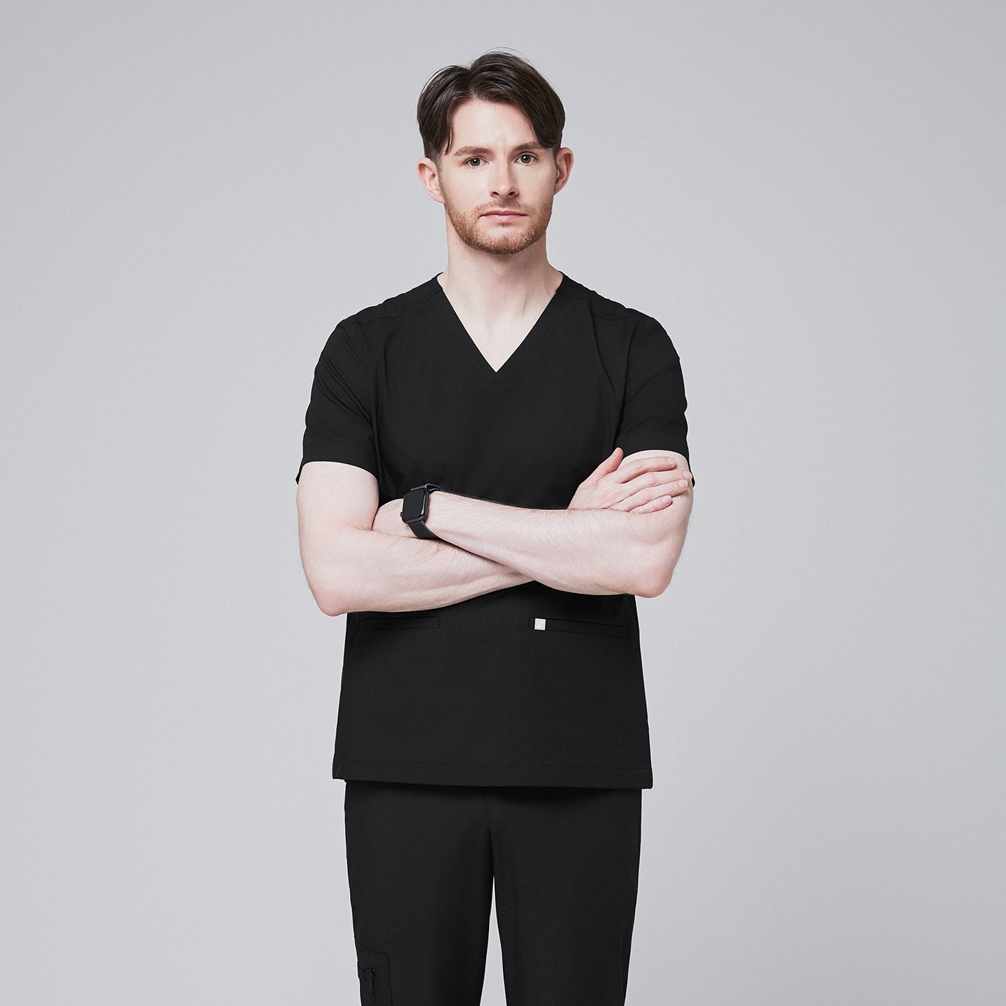 Man wearing black scrubs with a V-neck and double pockets, standing with arms crossed and a confident expression,Eco Black