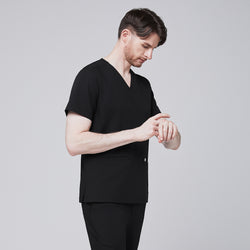 Image of Man in black scrubs with a V-neck and double pockets, checking the time on his smartwatch,Eco Black