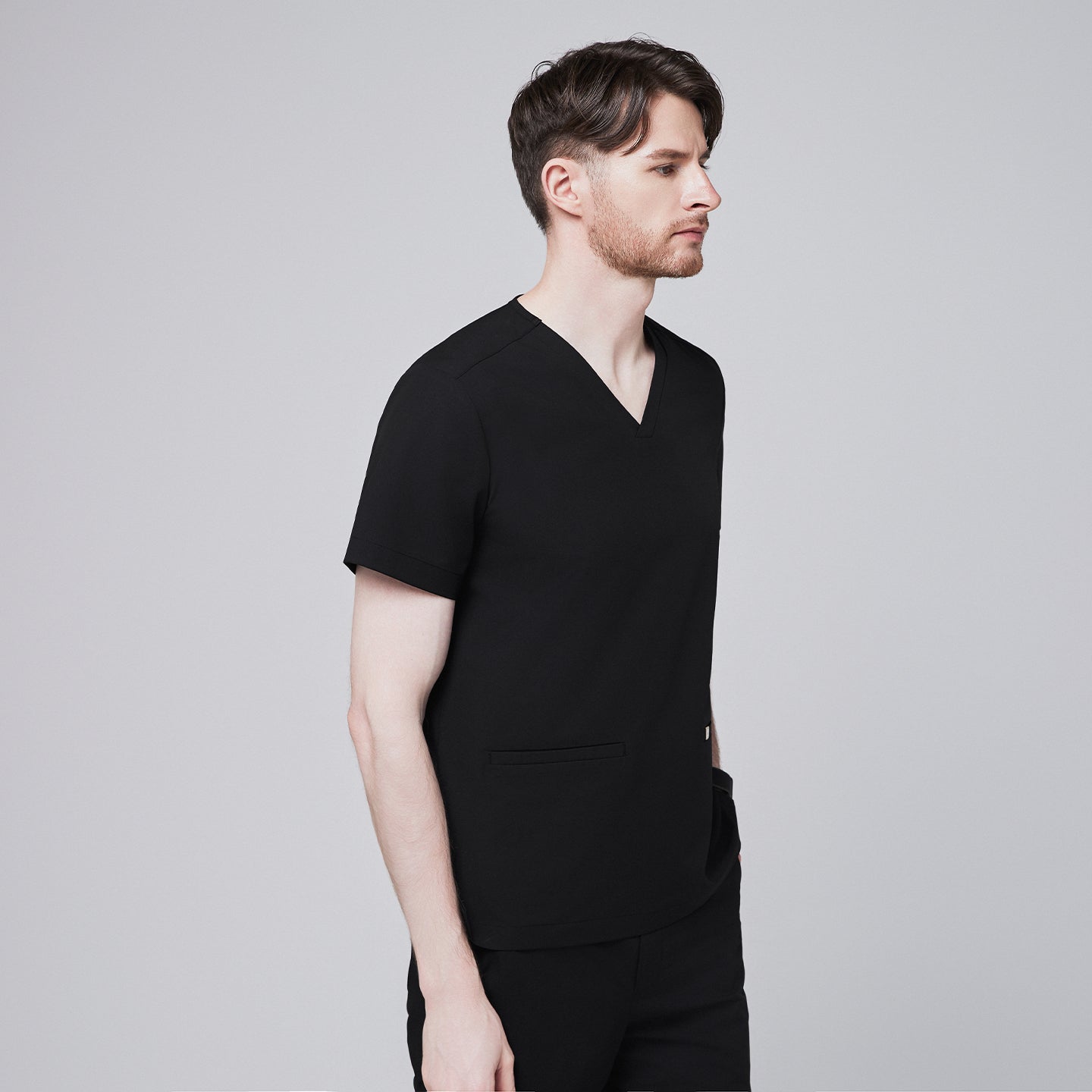 Man in black scrubs with a V-neck and double pockets, looking straight ahead,Eco Black