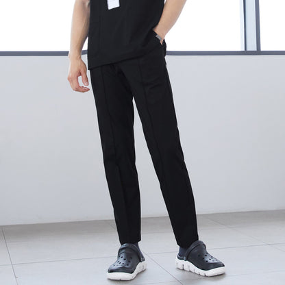 Close-up of man wearing front zipper scrub top with chest and side pockets, paired with straight-leg scrub pants, standing indoors with hands in pockets,Eco Black