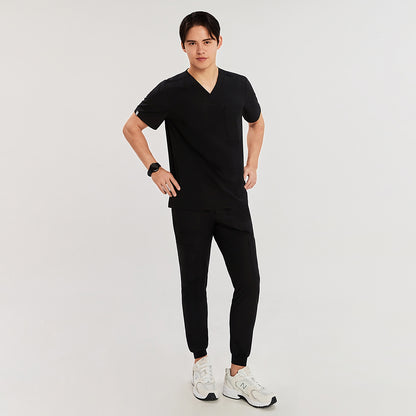 Full-body shot of a man wearing a V-neck scrub top with chest pocket, paired with jogger-style scrub pants, hands on hips, standing against a plain background,Eco Black