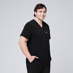 Image of Man in a black scrub set with a single-pocket V-neck top, standing with one hand in his pocket,Eco Black