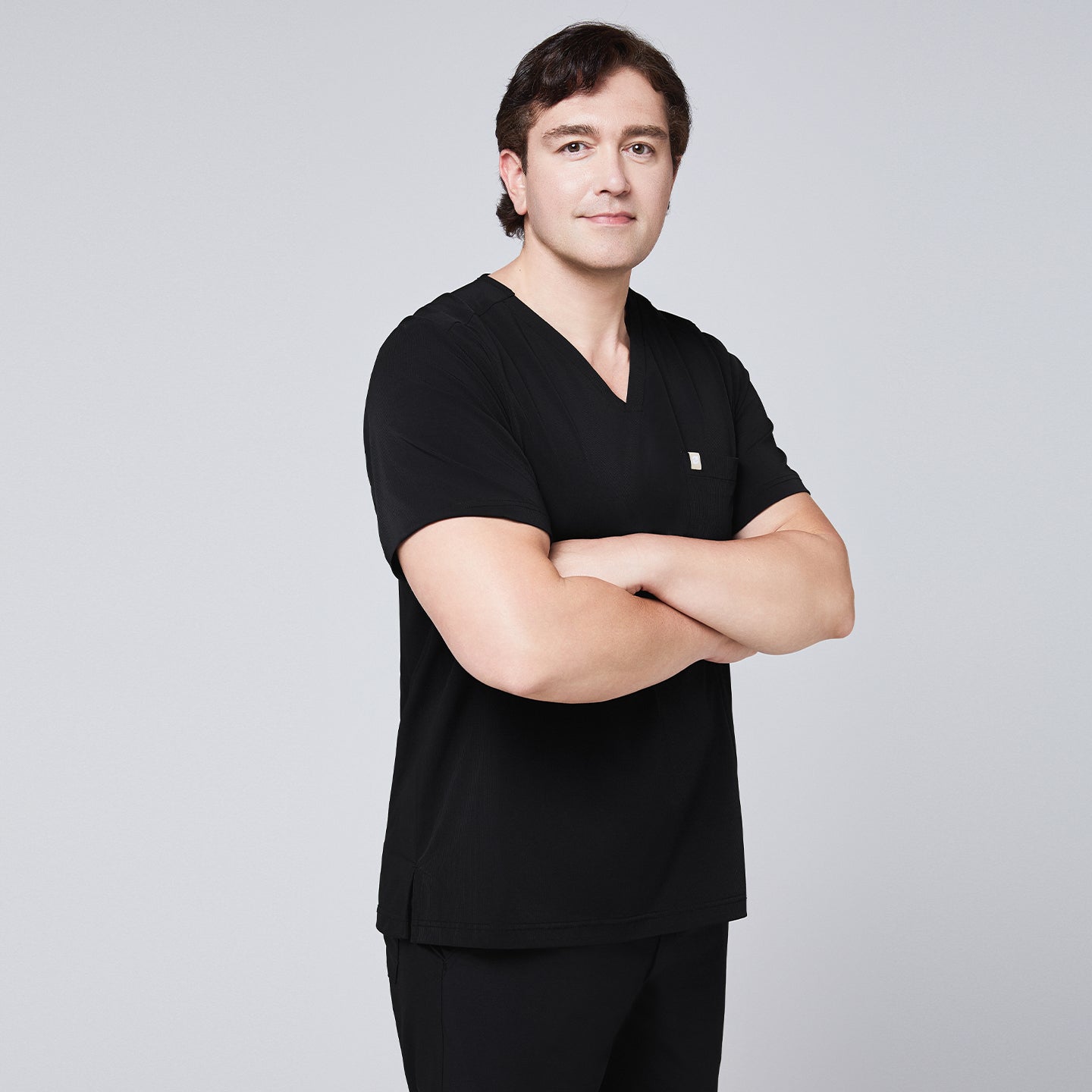 Man in a black scrub set with a single-pocket V-neck top, arms crossed in a confident pose,Eco Black