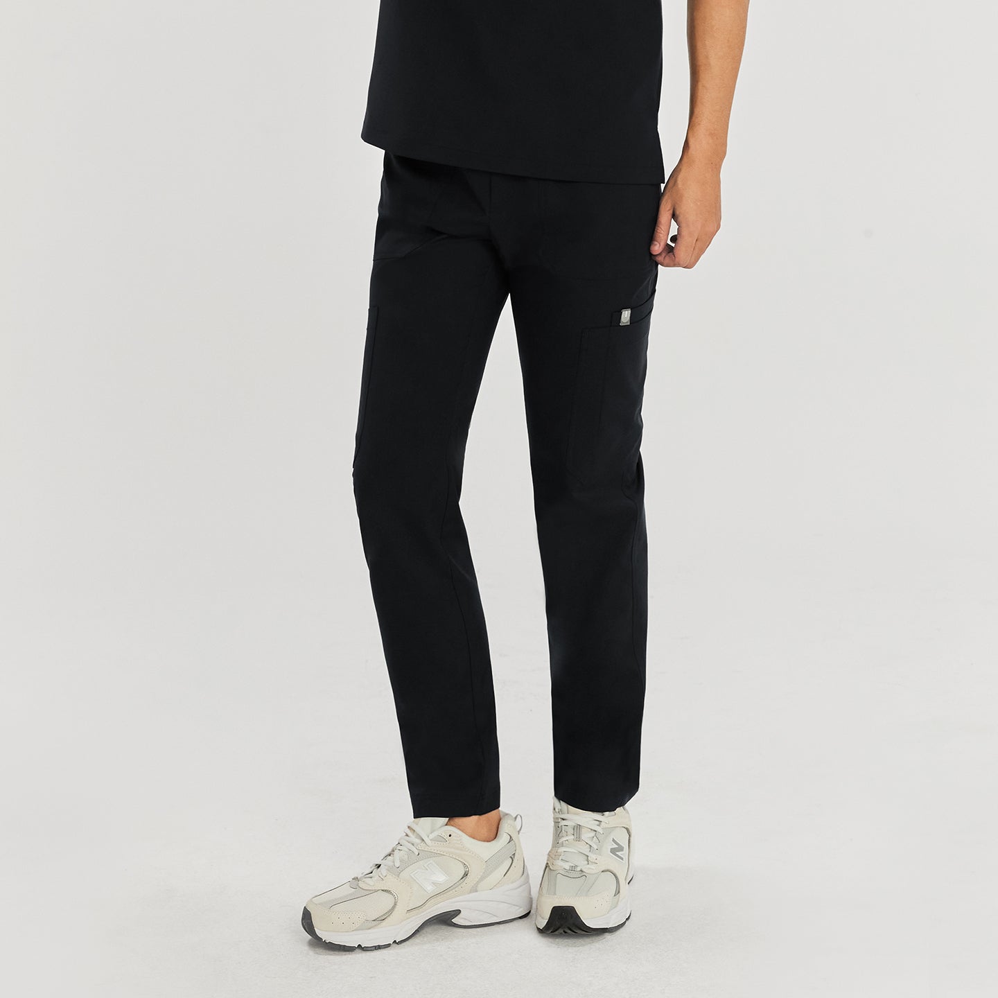 Model wearing zipper straight scrub pants with zipper details and side pockets, paired with a V-neck scrub top and white sneaker,Eco Black