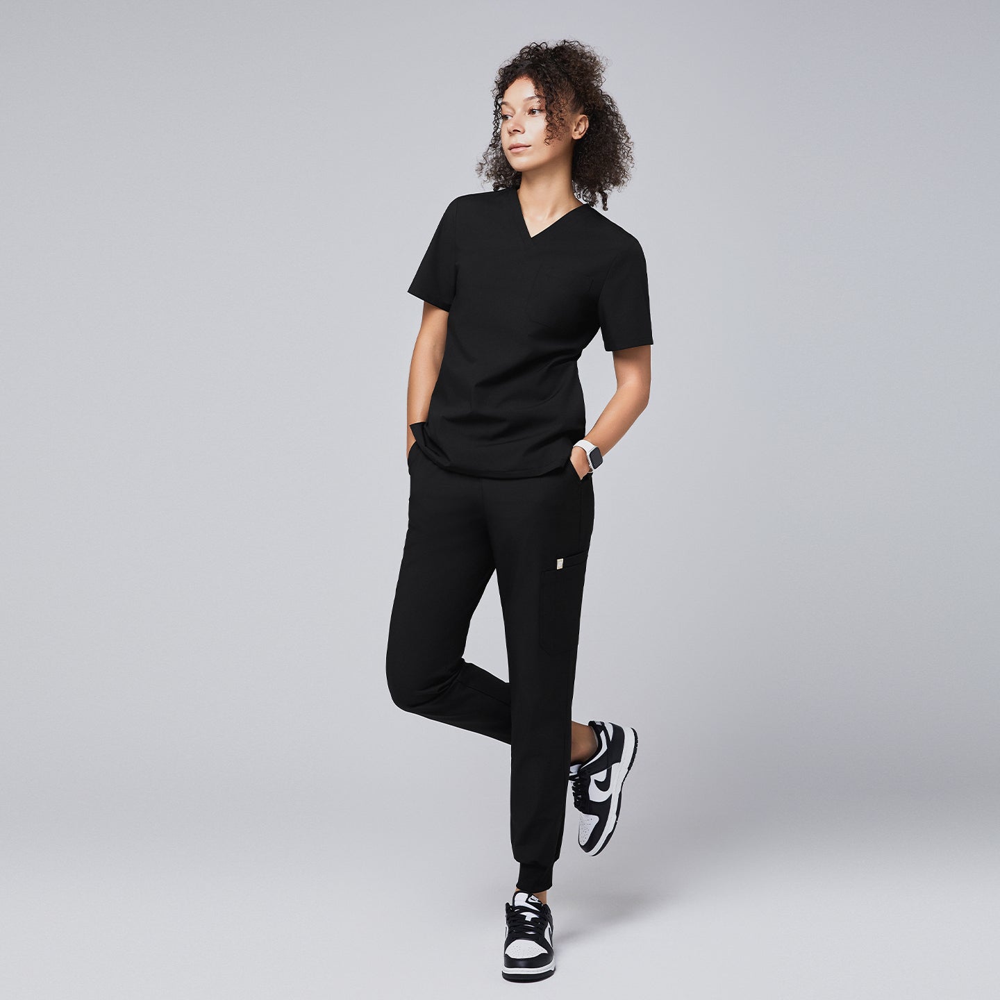 Black jogger scrub pants with a side pocket, elastic cuffs, and a clean design, paired with black-and-white sneakers and a yellow stethoscope,Eco Black