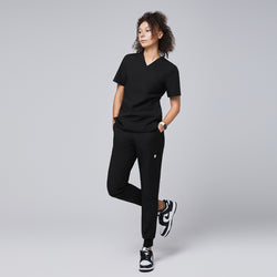 Image of Black jogger scrub pants with a side pocket, elastic cuffs, and a clean design, paired with black-and-white sneakers and a yellow stethoscope,Eco Black