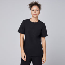 Image of Model wearing an eco black scrub top with a quarter zipper, facing forward with a neutral expression,Eco Black