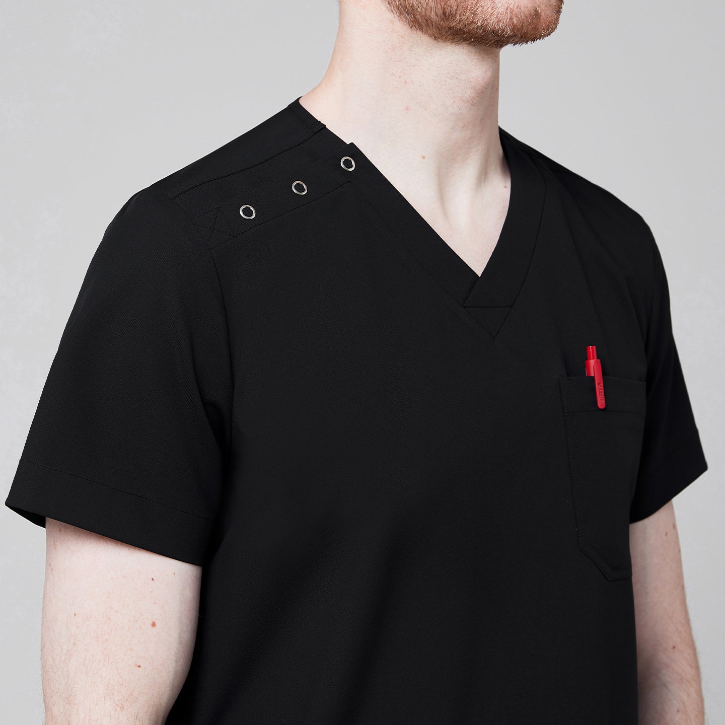 Close-up of Zenir black shoulder button scrub top with a red pen in the chest pocket and button details on the shoulder,Eco Black