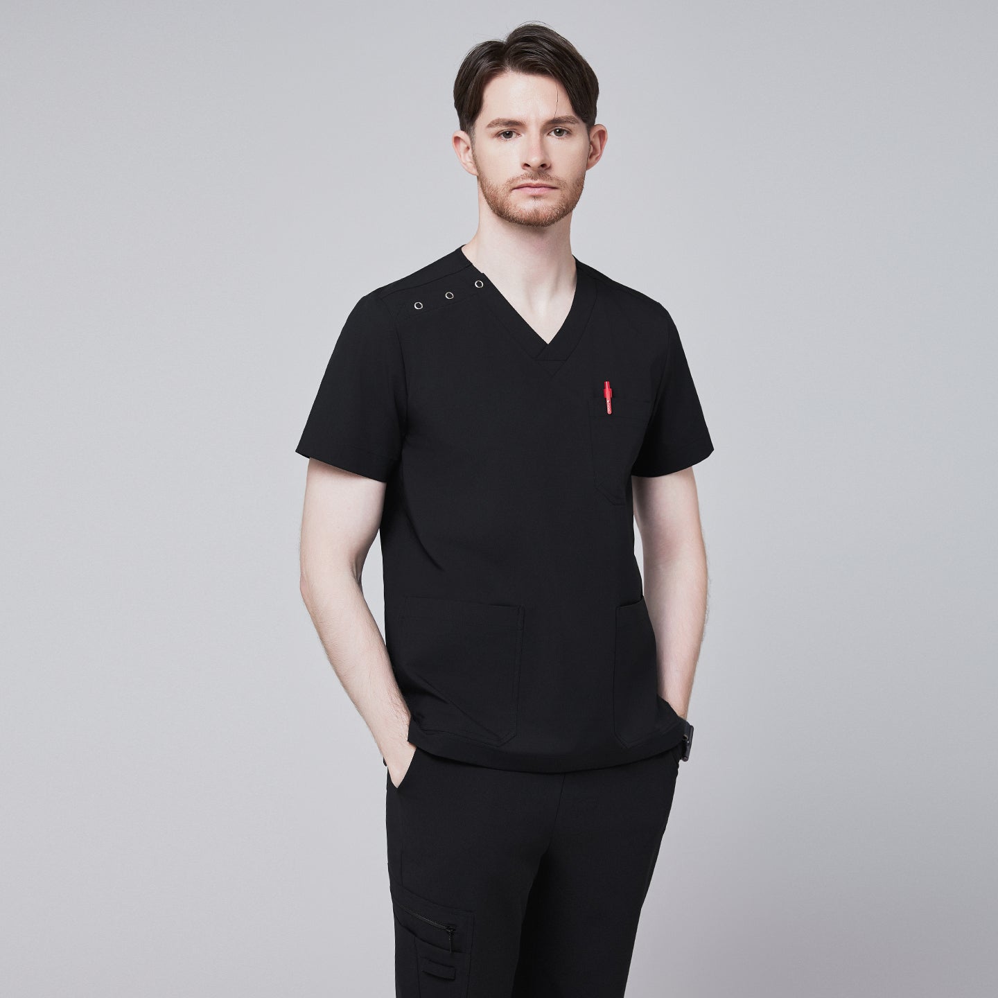 Man wearing Zenir black shoulder button scrub top with chest and lower pockets, featuring a red pen in the chest pocket,Eco Black