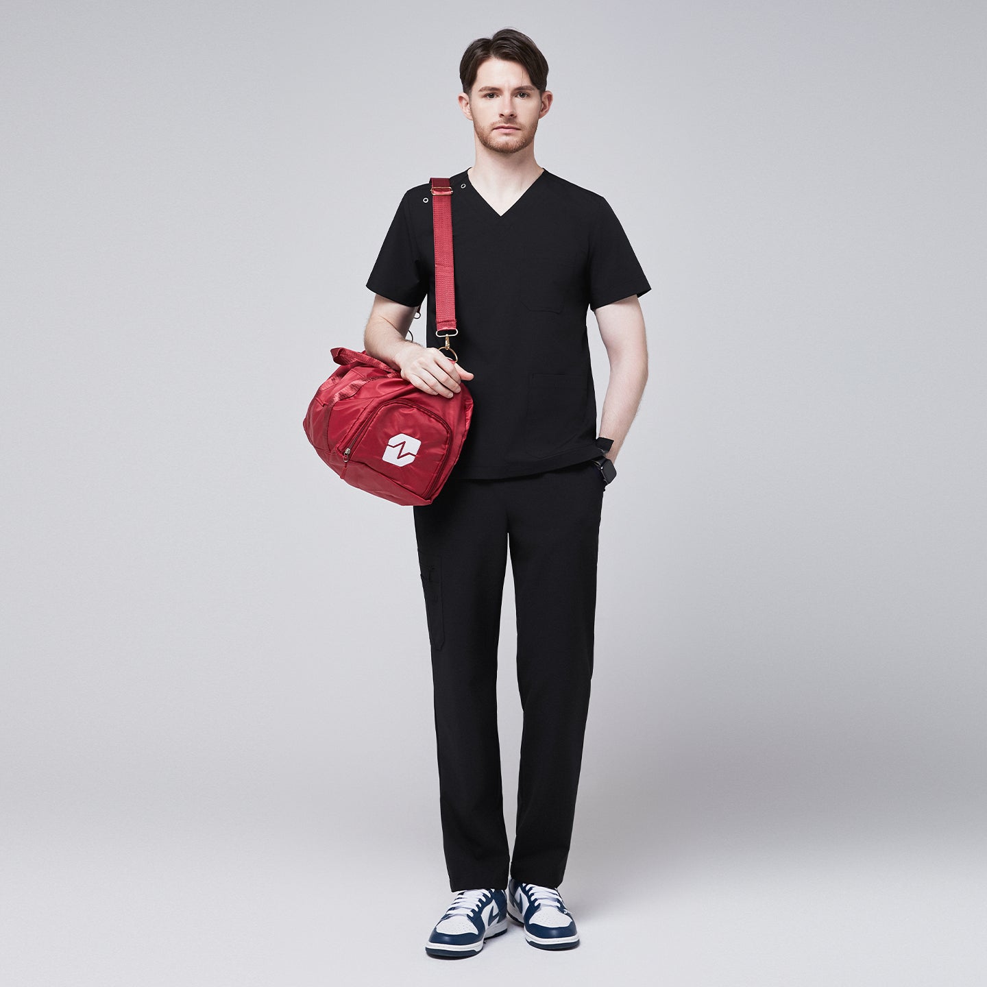 Man wearing Zenir black shoulder button scrub top with chest and lower pockets, featuring a red pen in the chest pocket,Eco Black