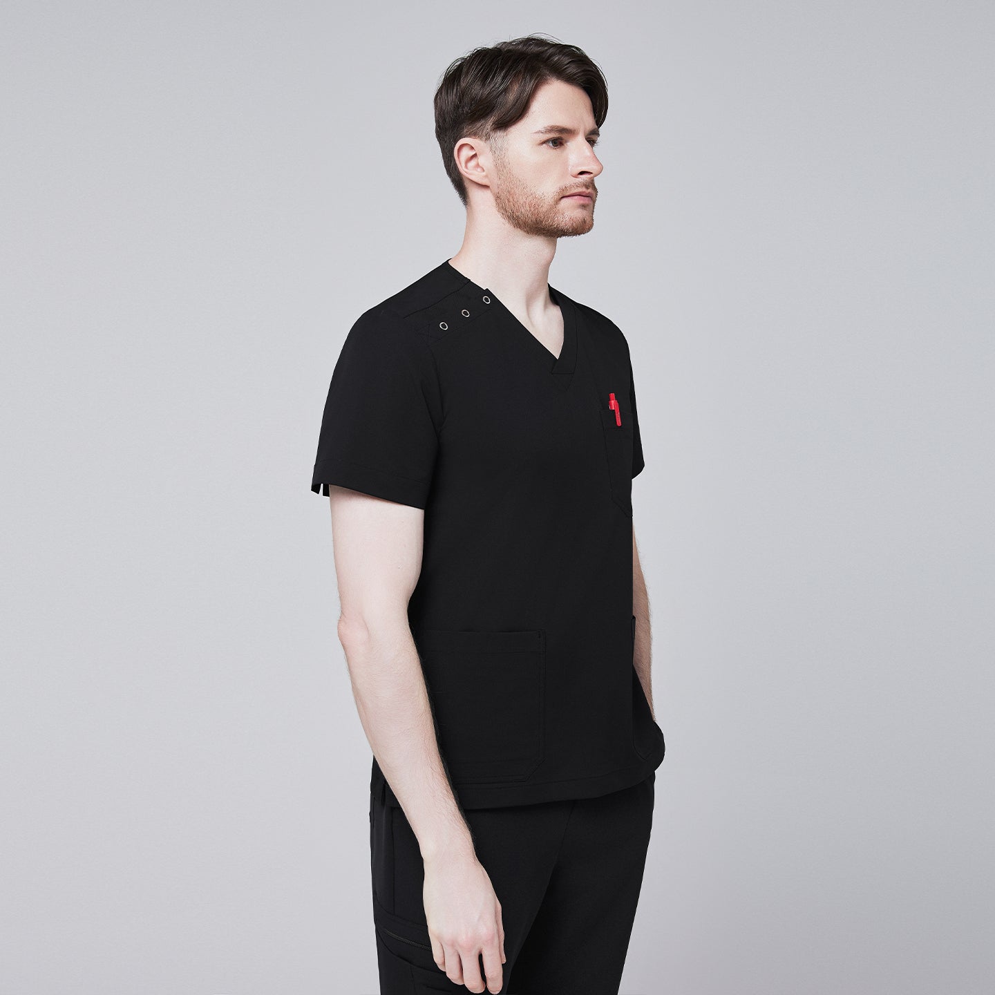 Man wearing Zenir black shoulder button scrub top with side profile, featuring chest and lower pockets and a red pen in the chest pocket,Eco Black