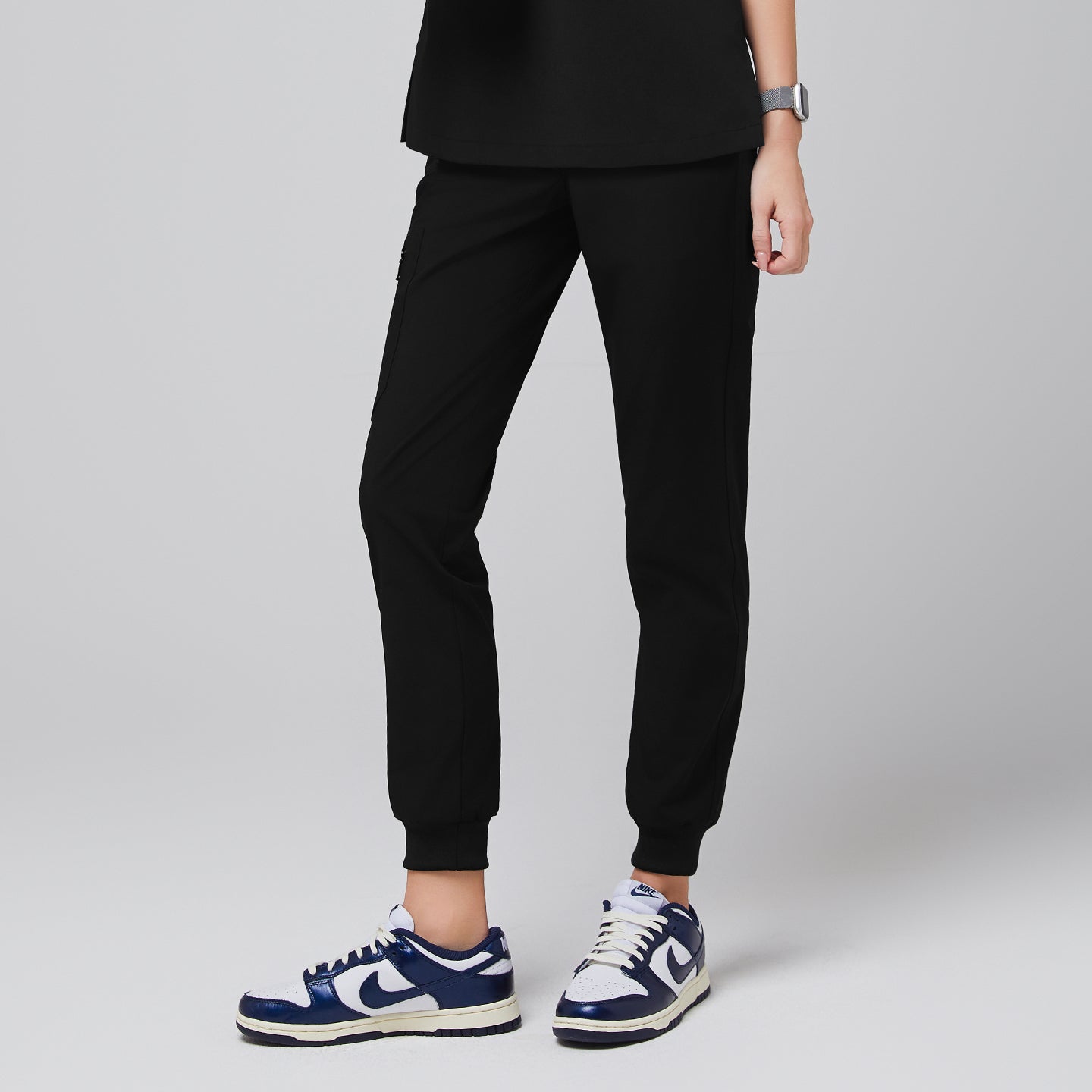 Eco black jogger scrub pants with zipper pocket and elastic cuffs, paired with navy sneakers,Eco Black