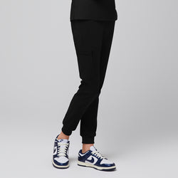 Image of Side view of eco black jogger scrub pants with zipper pocket and elastic cuffs, paired with navy sneakers,Eco Black