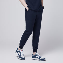 Image of Side angle of navy jogger scrub pants with 8 pockets, drawstring waistband, cuffed ankles, and a name badge, paired with navy sneakers,Eco Navy