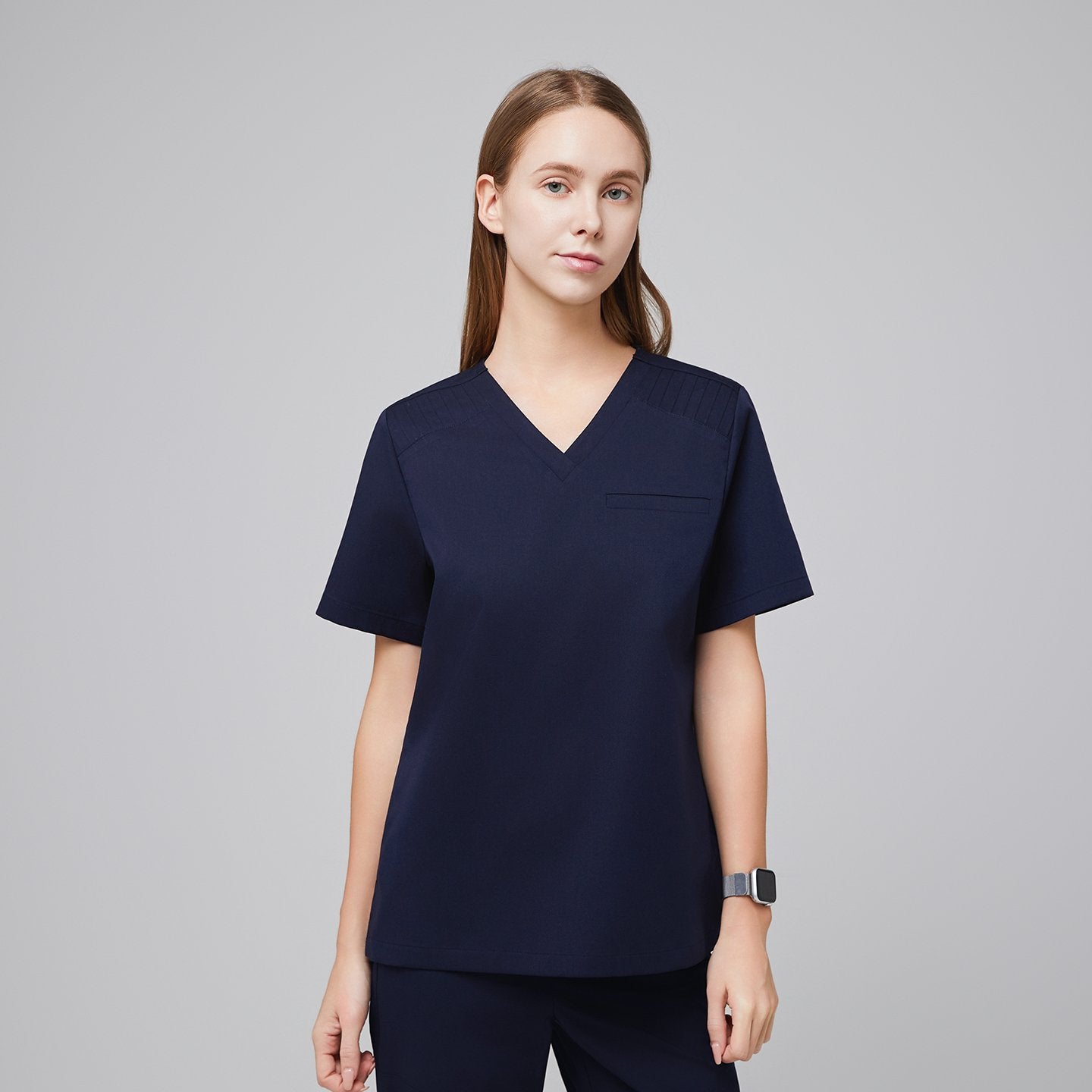 A woman wearing an Eco Navy Pleated Shoulder Scrub Top, part of a matching scrub set,Eco Navy