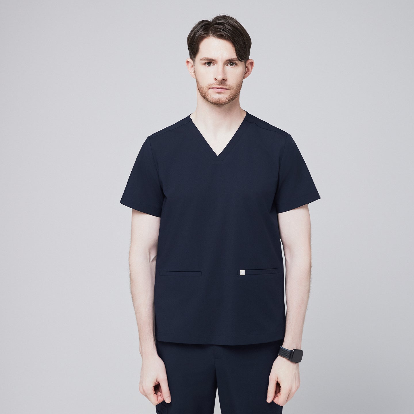 A man wearing an Eco Navy Double Pocket Scrub Top with short sleeves, part of a matching scrub set,Eco Navy