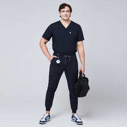 Image of Male healthcare professional wearing a navy scrub set with jogger-style pants, holding a black medical bag,Eco Navy