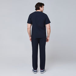 Image of Back view of a man wearing a navy scrub set, featuring straight-leg pants and a short-sleeve top,Eco Navy