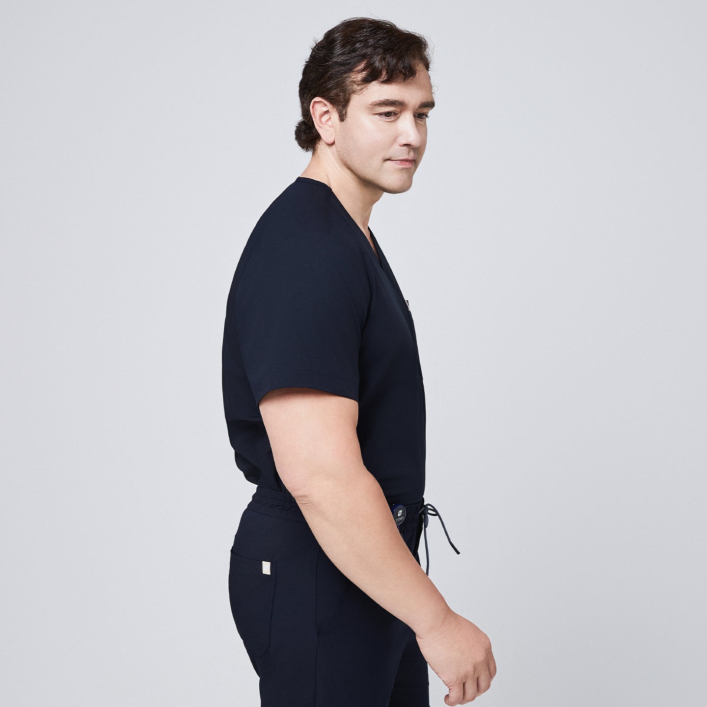 Side profile of a man wearing a navy scrub set with a drawstring waistband and a single-pocket top,Eco Navy