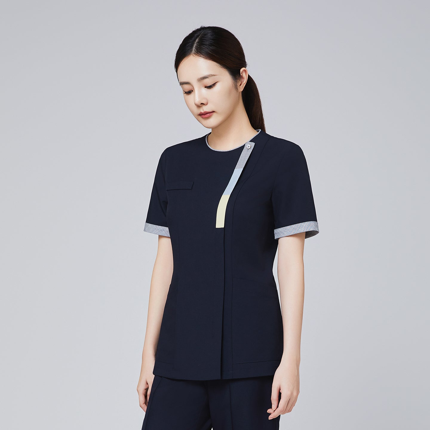 Professional navy scrub top with triple-tone detailing on the front zipper and sleeves, modeled by a woman,Eco Navy