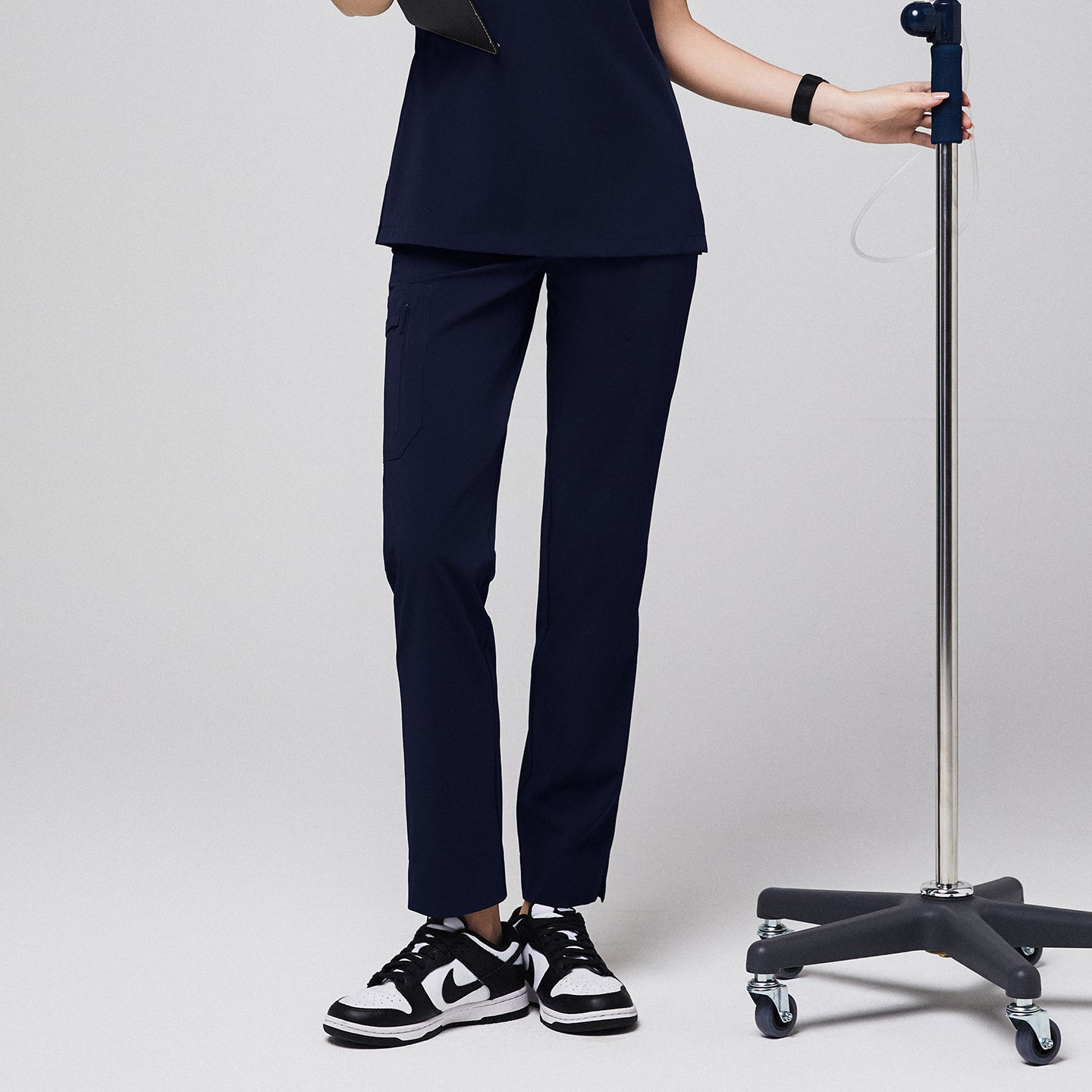 Navy scrub pants with zipper pocket and split hem, paired with black sneakers and matching top,Eco Navy