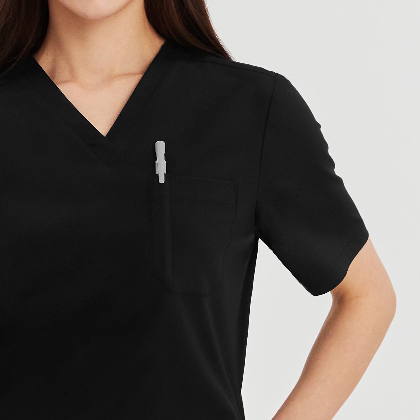 Close-up of chest pocket with pen on black Zenir scrub top worn by a woman,Eco Black