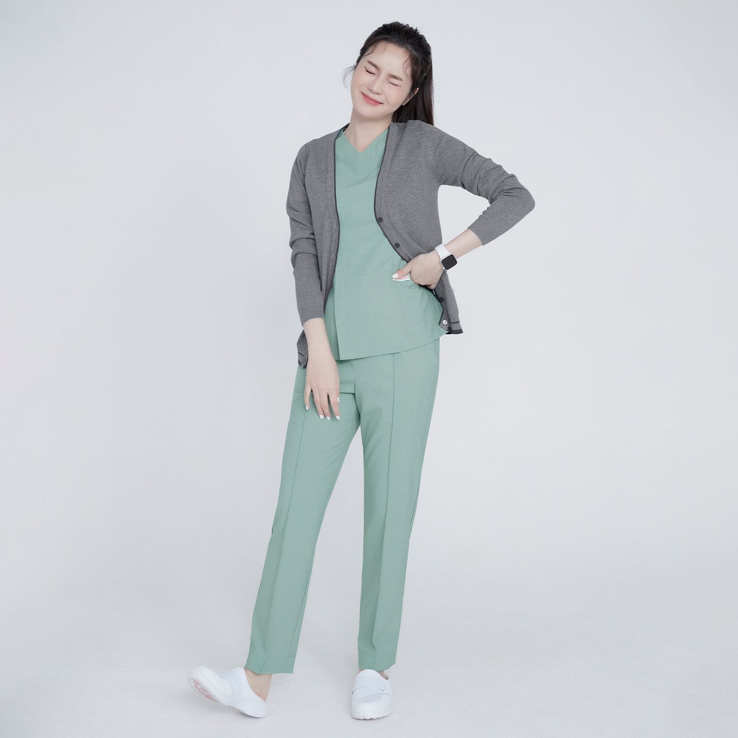 Woman wearing a gray soft touch cardigan over a green top and pants, posing with one hand on her hip and eyes closed,Gray