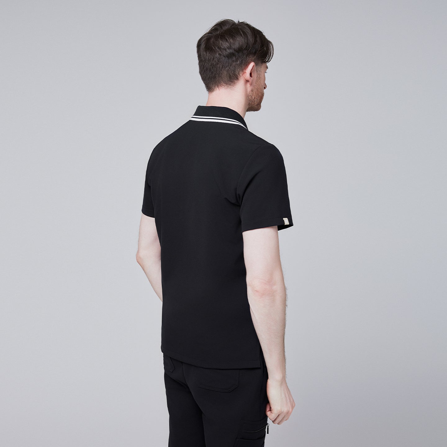 Male model showcasing the jet black performance polo scrub top with a striped collar, focusing on fit and design,Jet Black