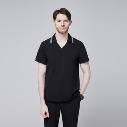 Image of Male model wearing a jet black performance polo scrub top with a striped collar and matching pants, standing with one hand in pocket,Jet Black