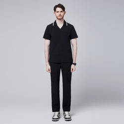 Image of Male model wearing a jet black performance polo scrub top with a striped collar and matching pants, standing straight with sneakers,Jet Black