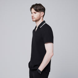 Image of Side profile of a male model wearing a jet black performance polo scrub top with a striped collar and hands in pockets,Jet Black