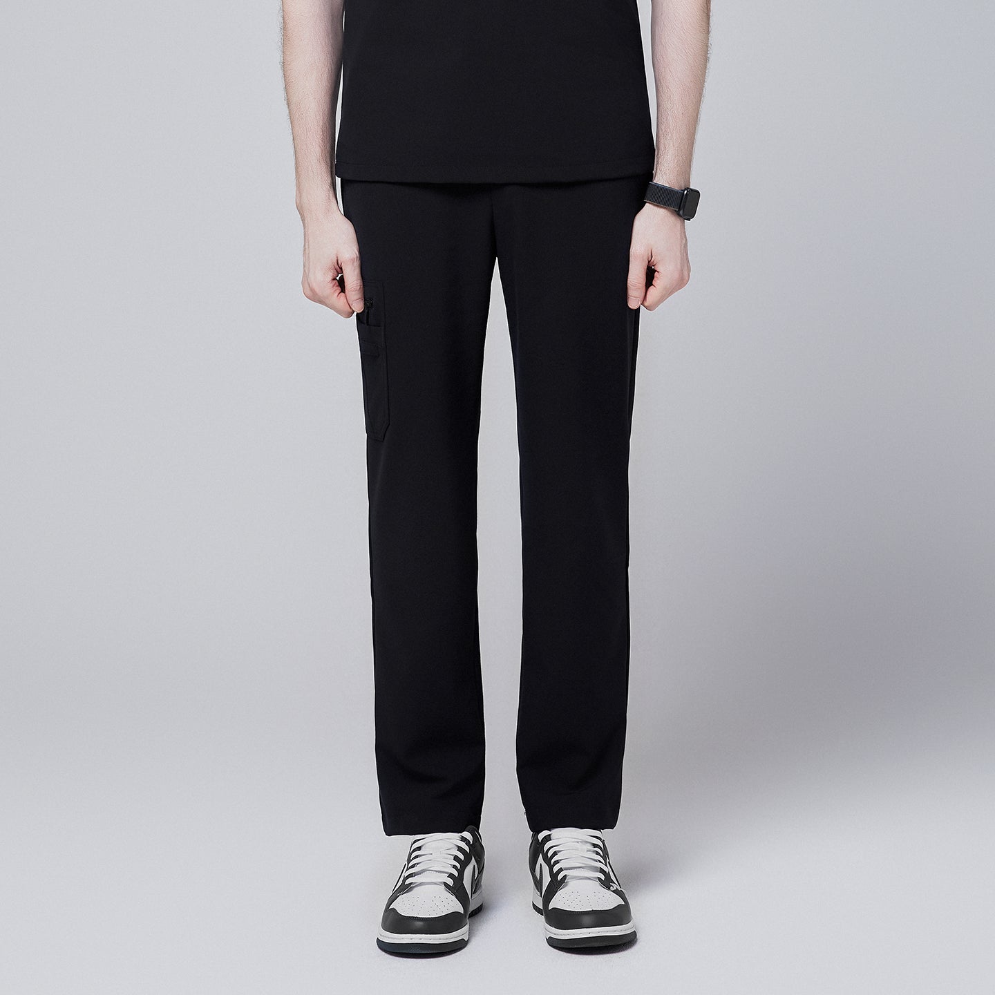 Male model standing upright, wearing jet black relaxed-fit scrub pants with side pocket detailing, demonstrating a professional and sleek appearance,Jet Black