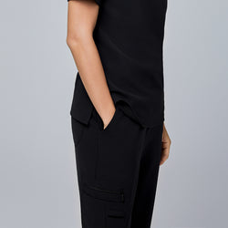 Image of Black utility scrub pants with a zippered side pocket and a sleek design, paired with a black top.Jet Black