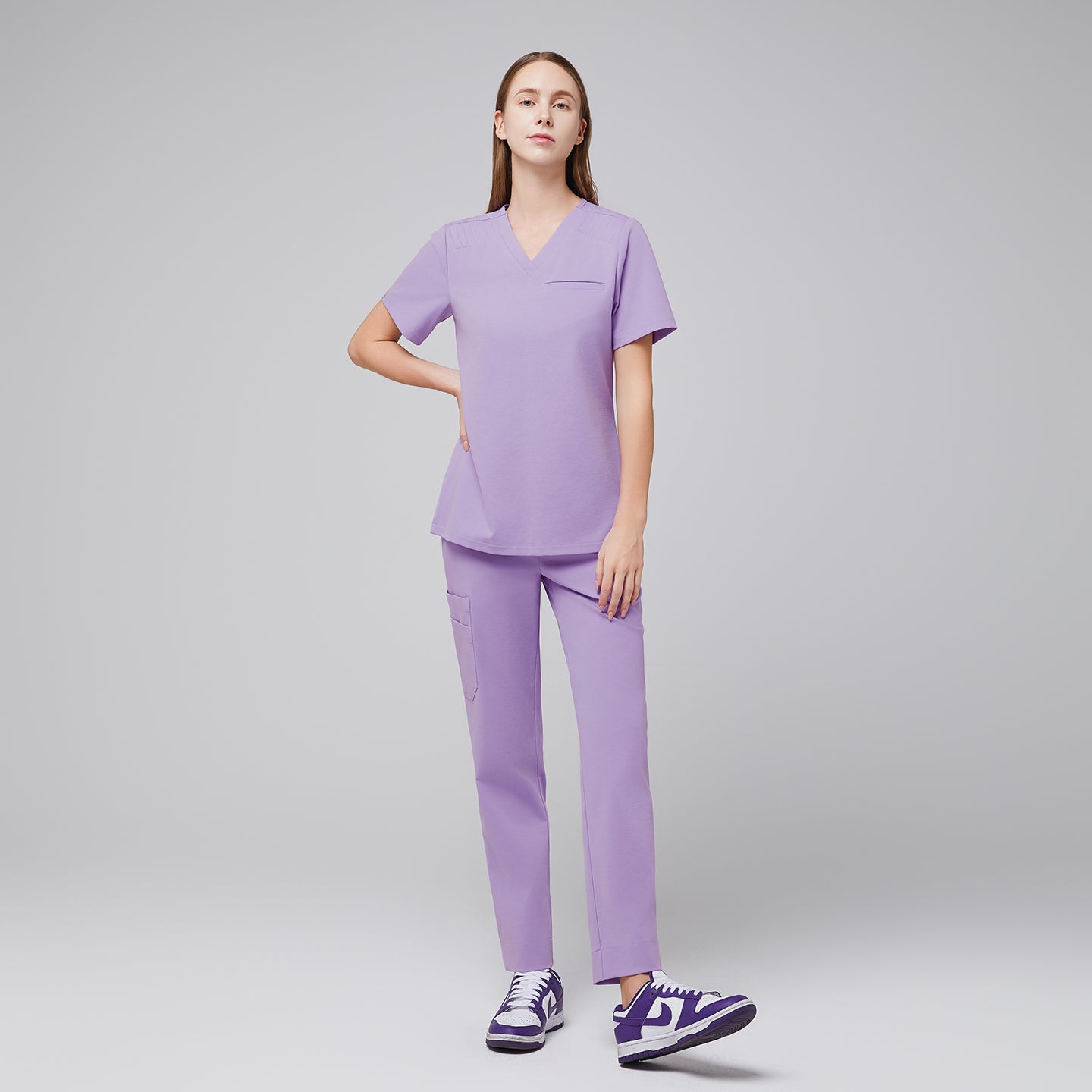 Lavender pleated shoulder scrub set with v-neck top and straight leg pants worn with purple sneakers,Lavender