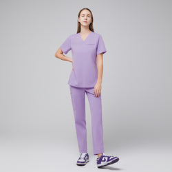 Image of Lavender pleated shoulder scrub set with v-neck top and straight leg pants worn with purple sneakers,Lavender