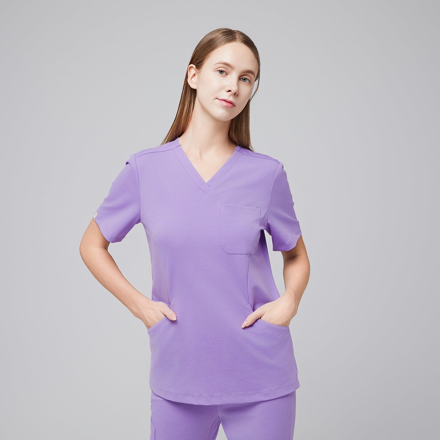 Woman wearing a lavender scrub top and pants, standing with hands in pockets, showcasing the comfort and practicality of the medical uniform,Lavender