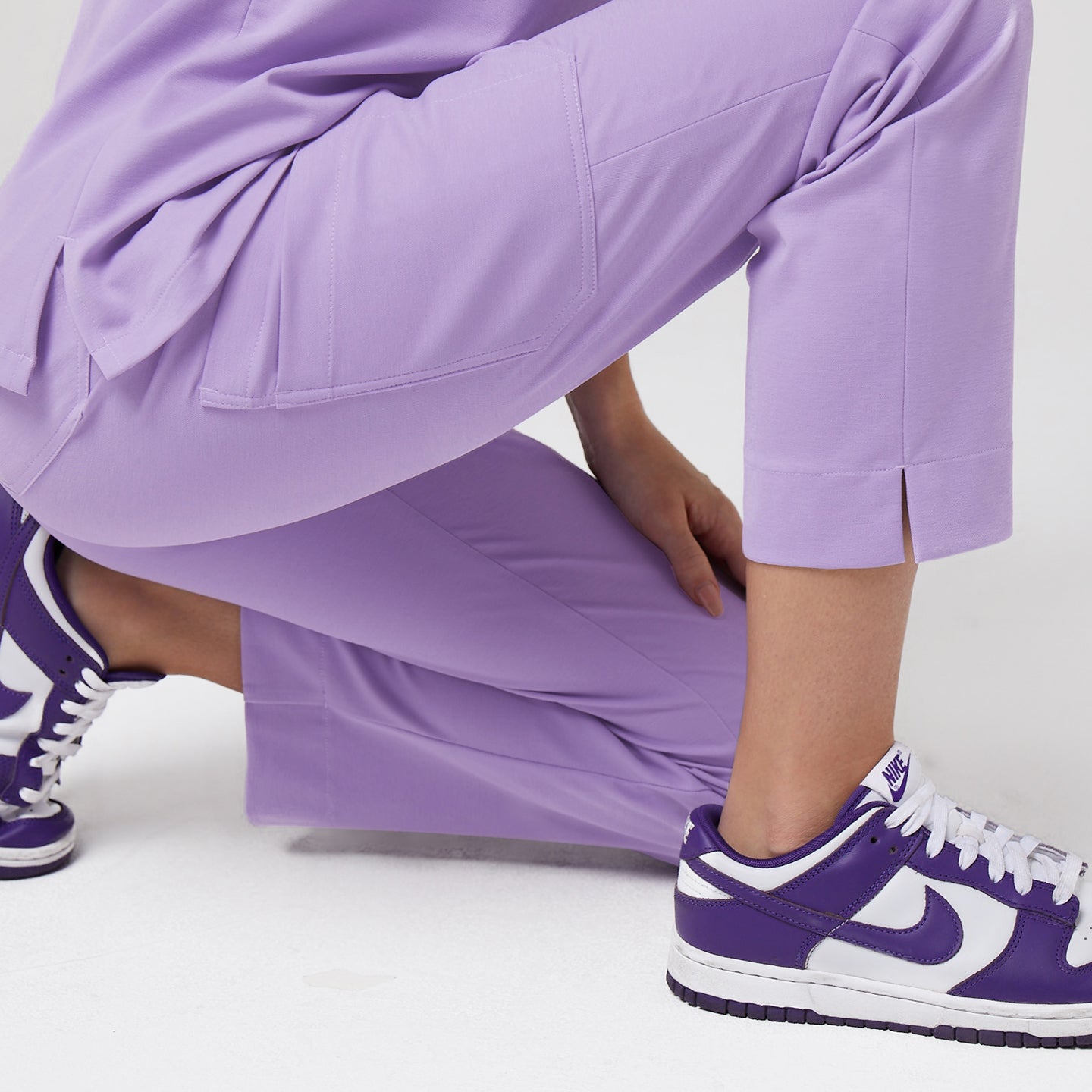 Detail of lavender scrub pants with side pocket and split hem, paired with purple sneakers,Lavender